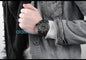 Alcom Distribution tactical luminous army watch worn on wrist over gray denim jacket showing rugged black design