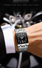 Alcom Distribution luxury men's quartz watch stainless steel rectangular black dial with Roman numerals on suited wrist