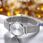 Elegant silver wristwatch with mesh strap by Alcom Distribution against blurred golden background