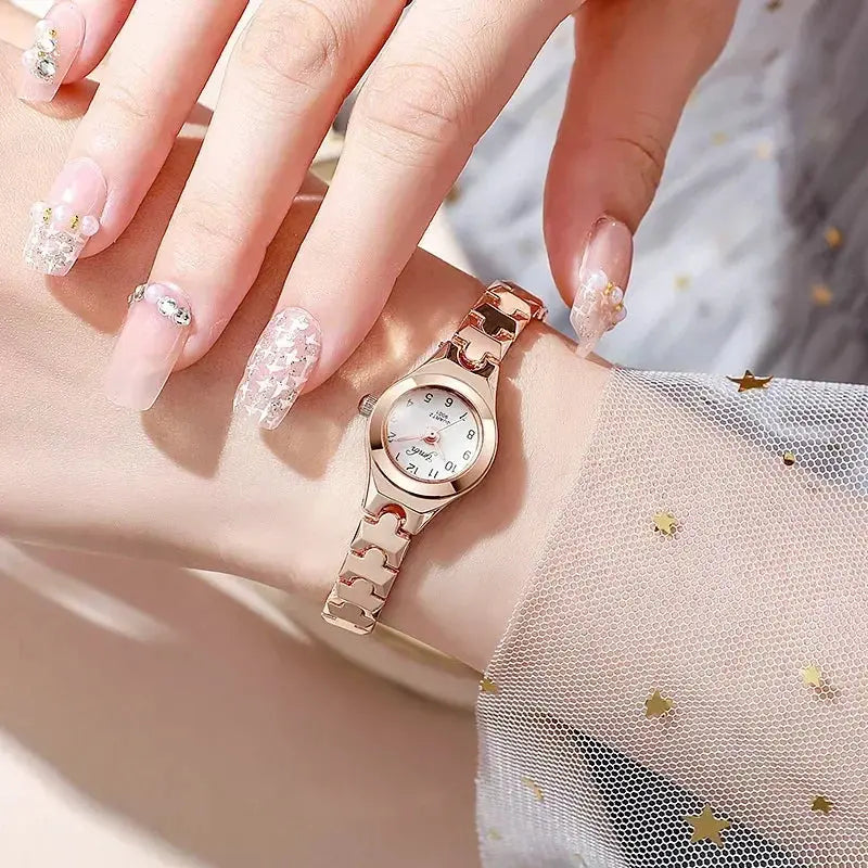 Alcom Distribution rose gold ladies bracelet watch on wrist with white dial linked bracelet and manicured nails