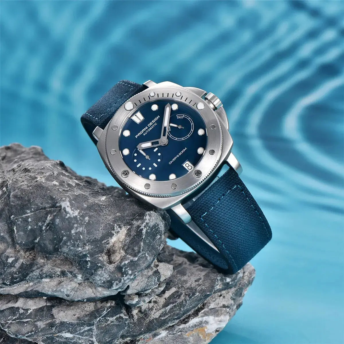 Pagani Design diver watch with blue dial and fabric strap displayed on a rock near water