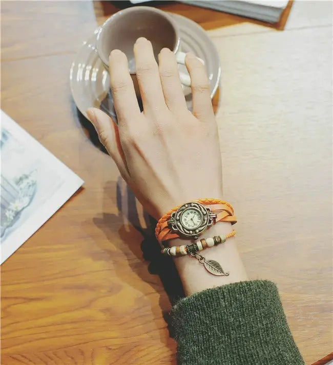 Shourui quartz wristwatch for women with orange braided strap and decorative charm bracelet on wrist