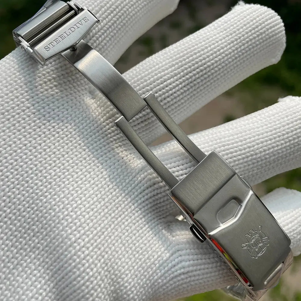 Stainless steel clasp and bracelet of Steeldive SD1970 automatic dive watch held by gloved hand