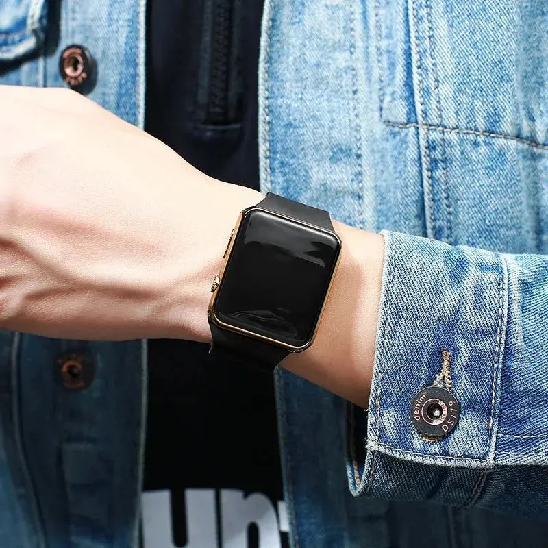 Alcom Distribution simple fashion digital watch black square face with gold bezel on wrist wearing denim jacket