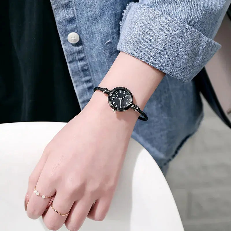 Alcom Distribution retro gold bangle watch with black dial worn on wrist with denim jacket