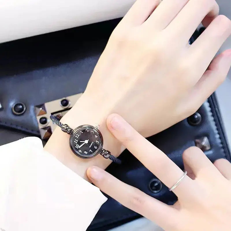 Alcom Distribution retro gold bangle watch with black dial worn on wrist over white sleeve