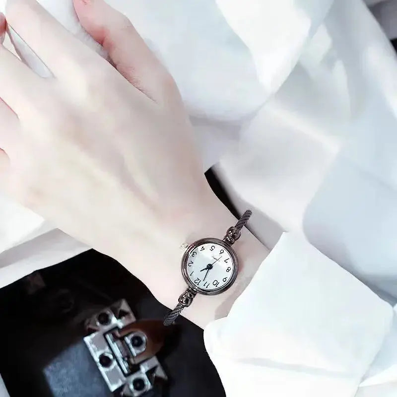 Alcom Distribution retro gold bangle watch with a round white dial on wrist in white shirt