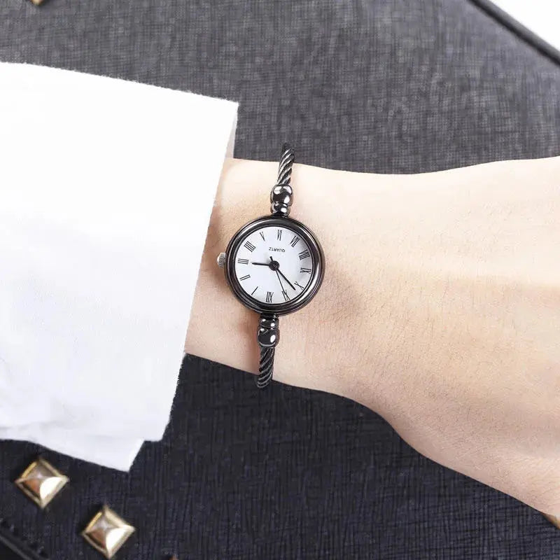 Black retro gold bangle watch with white dial and Roman numerals on wrist by Alcom Distribution