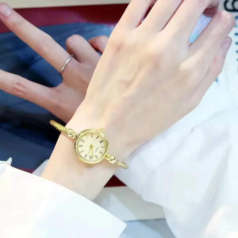Alcom Distribution retro gold bangle watch with round face and Roman numeral dial on wrist