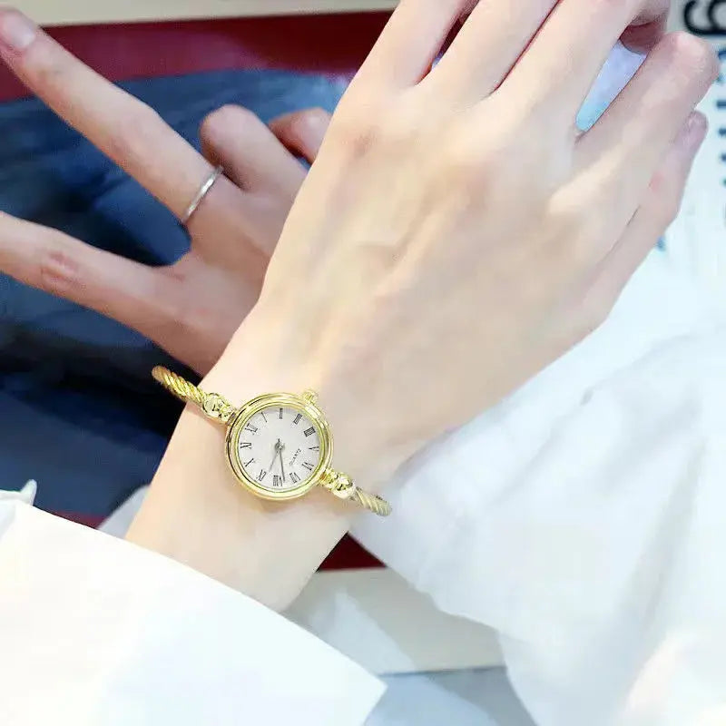 Alcom Distribution retro gold bangle watch with a round face worn on wrist