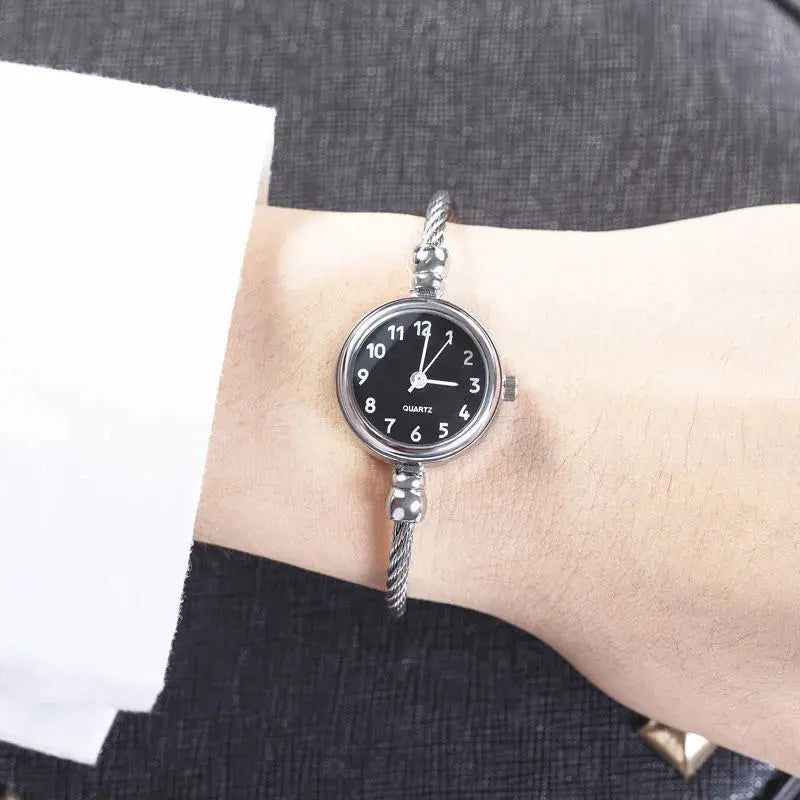Alcom Distribution silver watch with black dial and twisted metal band style similar to retro gold bangle watch