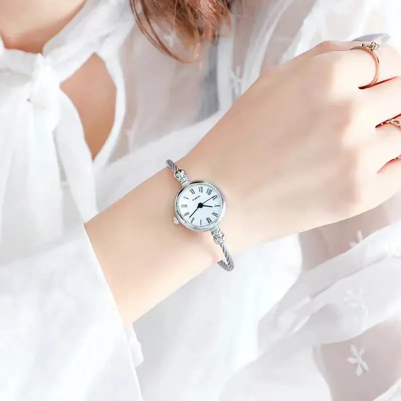 Retro gold bangle watch from Alcom Distribution worn on wrist with white dial and roman numerals