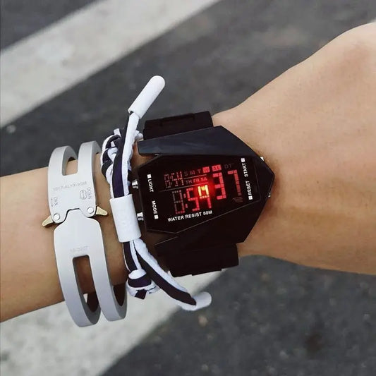Alcom Distribution aircraft-inspired digital watch with black strap on wrist showing red LED display