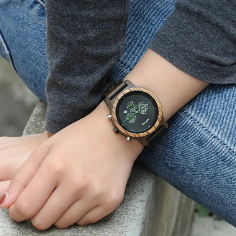 Alcom Distribution eco-friendly bamboo watch with black dial worn on wrist against denim jeans