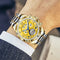 Stylish men's wristwatch with gold and silver metal band and yellow dial on wrist
