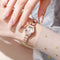 Alcom Distribution rose gold ladies bracelet watch on wrist with white dial linked bracelet and manicured nails