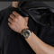 Luminous sports watch for men with black and gold dial worn on wrist by man in black shirt