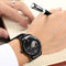 SKROX waterproof automatic watch with black dial and metal band worn on wrist while writing